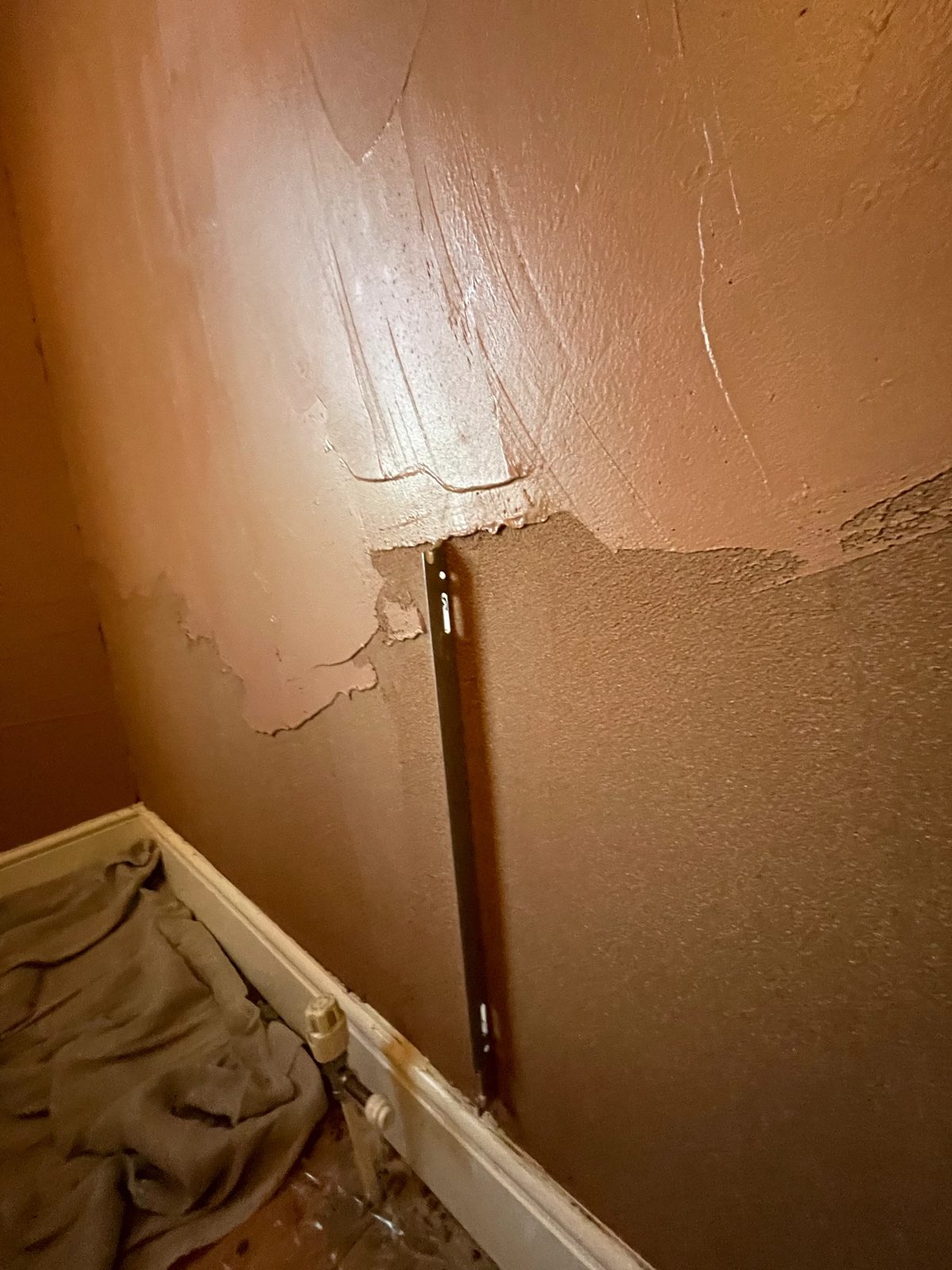 Skim coat being worked into a wall corner above a radiator