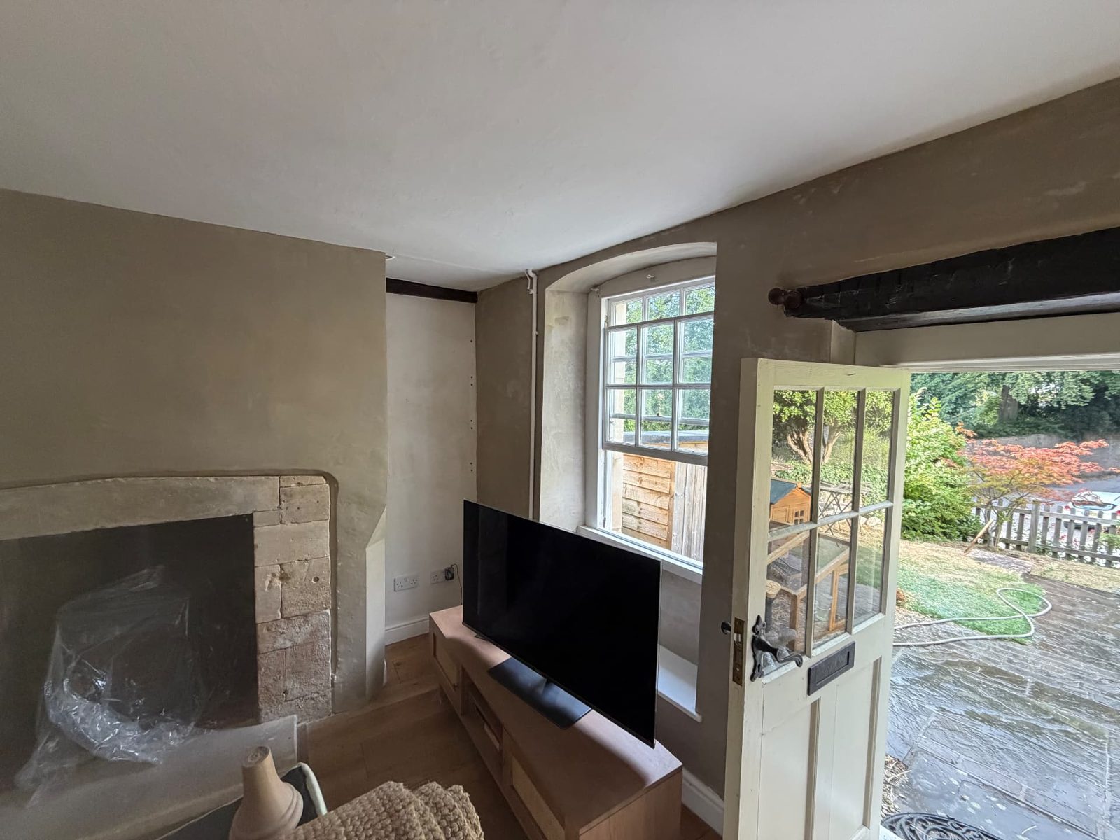 Cottage living room finished in breathable lime plaster around a stone fireplace