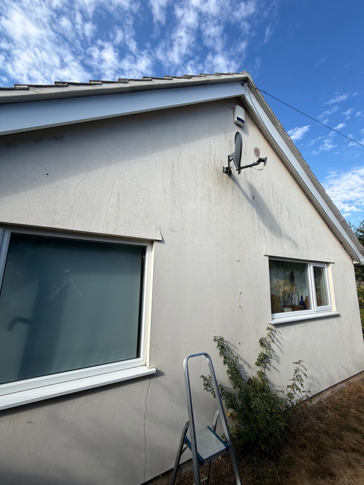 Before work in Frome: pale rendered gable wall with visible cracks and weather staining around two windows