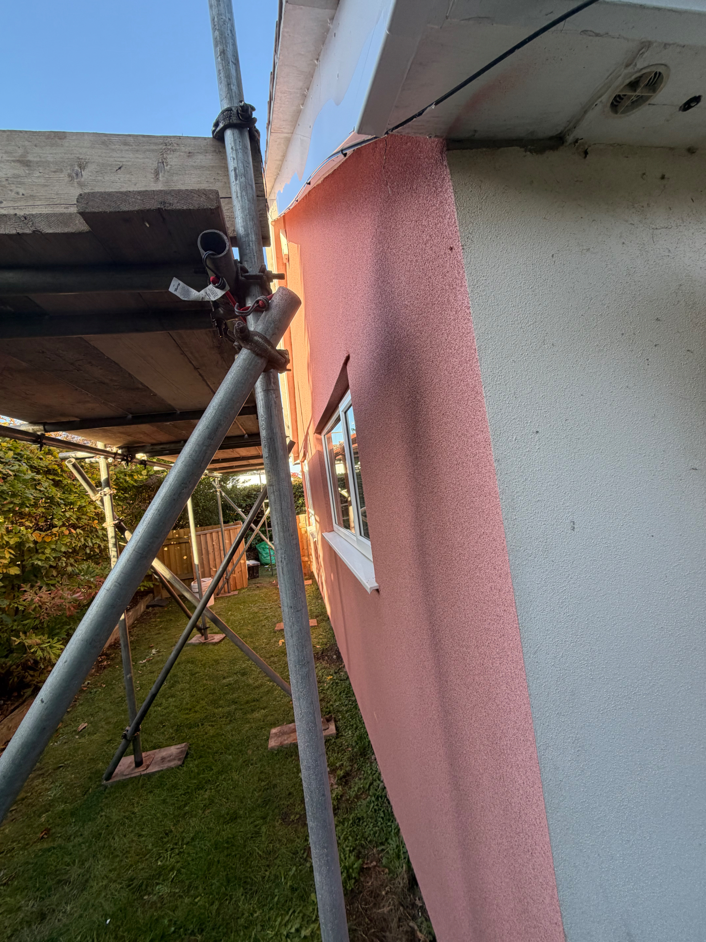 Mid-job in Frome: the new blush pink cork coating on one elevation beside the original pale render on the next