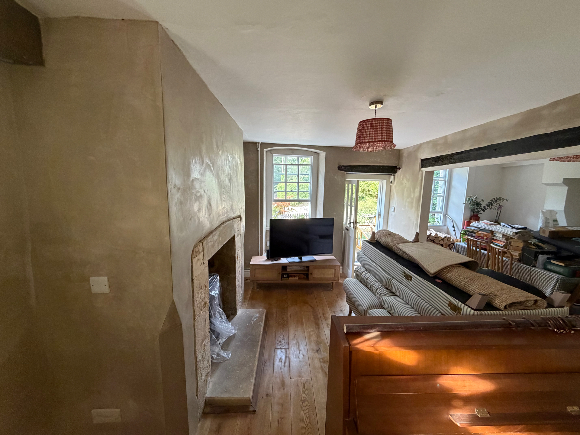 Living room with breathable lime plaster on the walls around a stone fireplace, a DSB lime plastering job in Bathford