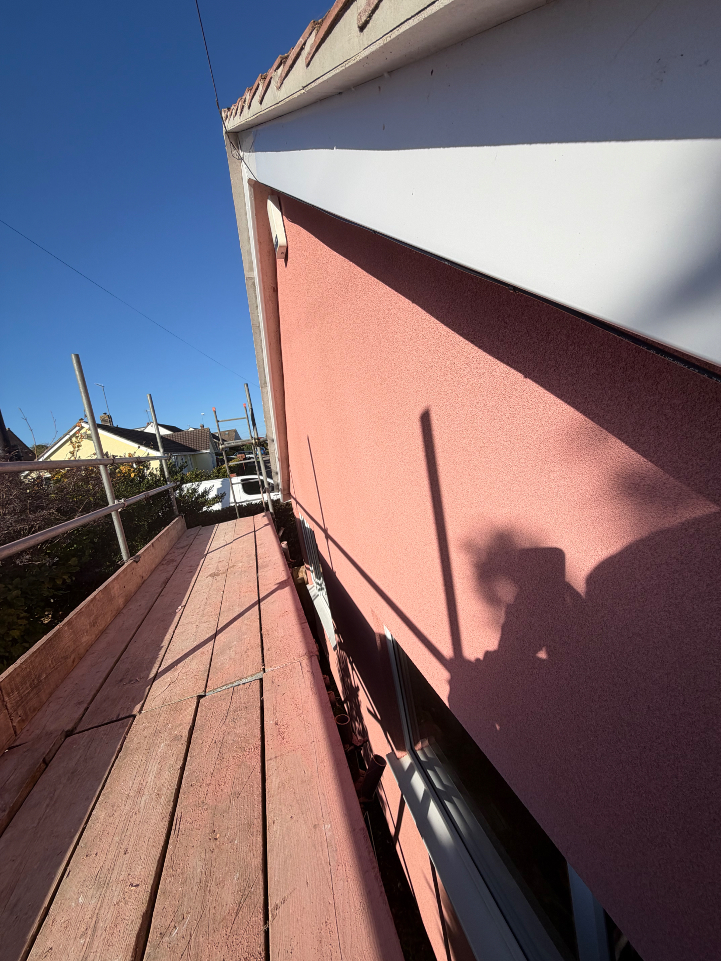 Finished blush pink spray cork coating on the gable wall in Frome, seen from the scaffold boards