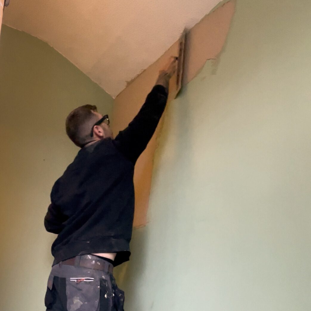 DSB plasterer skimming the top of a wall where it meets the ceiling