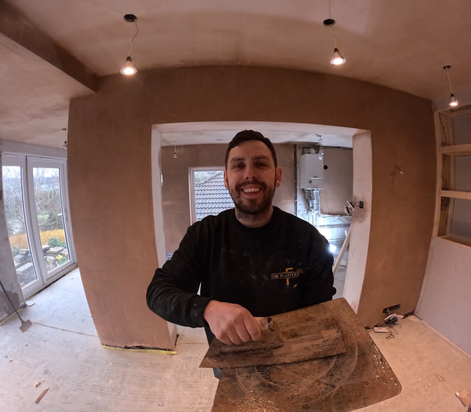 DSB plasterer in branded workwear holding a trowel in a freshly plastered room