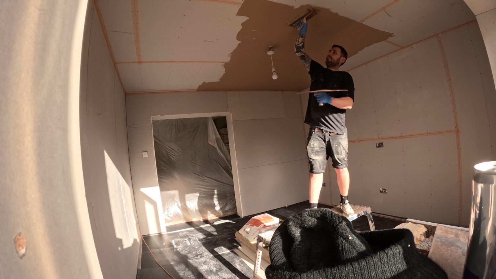 Plasterer working a smooth skim coat across a new ceiling