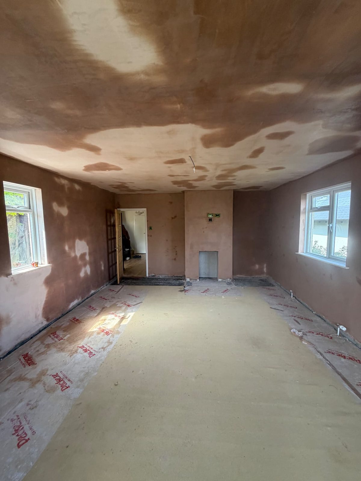 Large room fully replastered — walls and ceiling skimmed with the floor protected