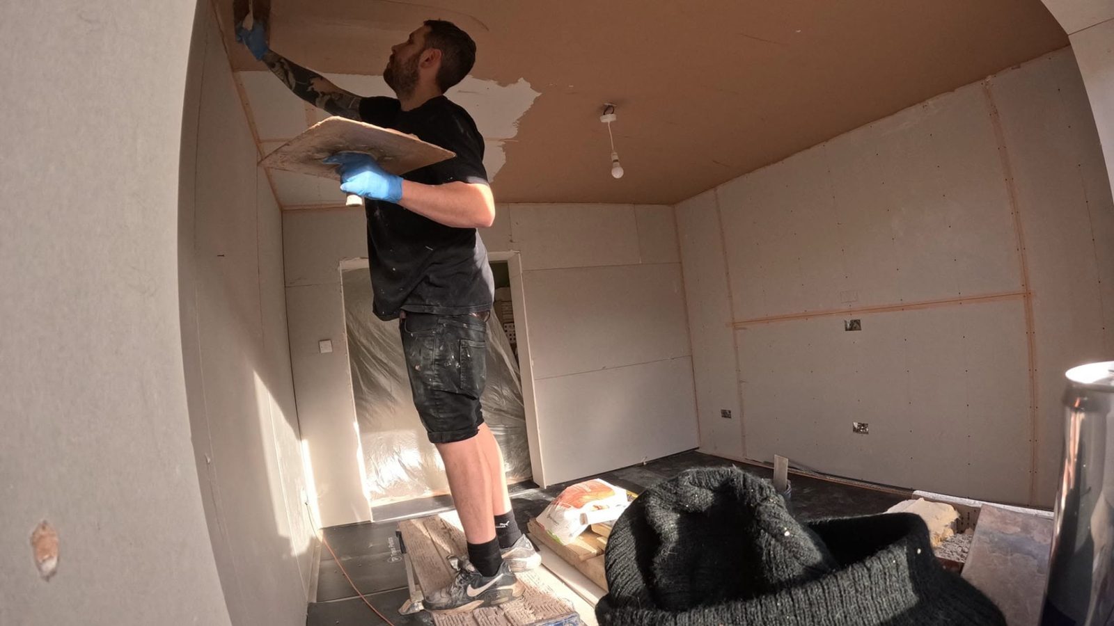 DSB plasterer applying plaster to a boarded ceiling with a trowel