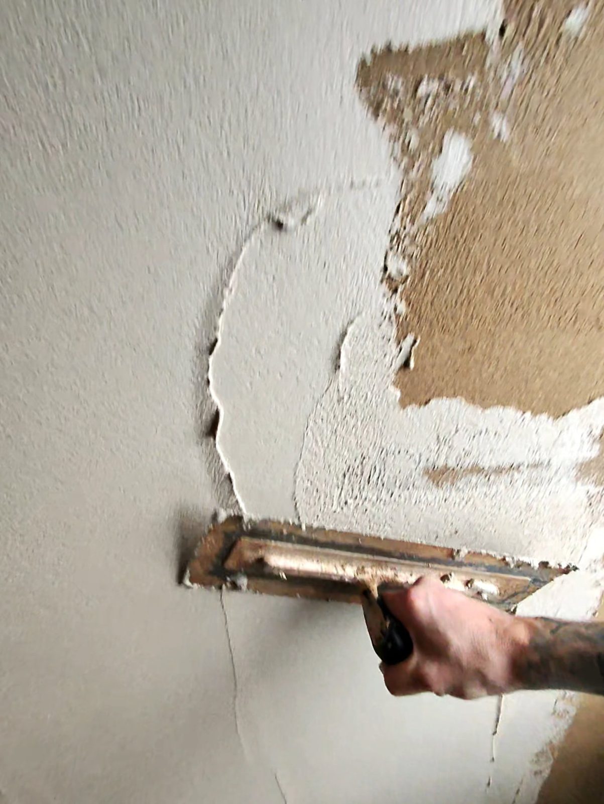 Grey lime plaster coat being applied over the backing coat on a wall