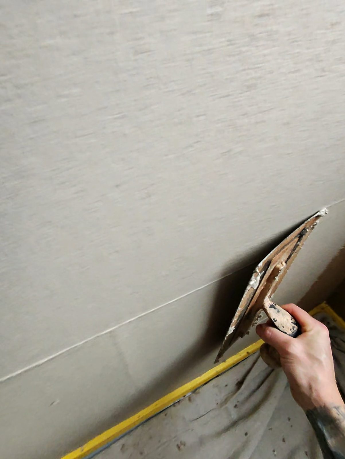 Lime plaster being flattened off along a masked wall in a Victorian property